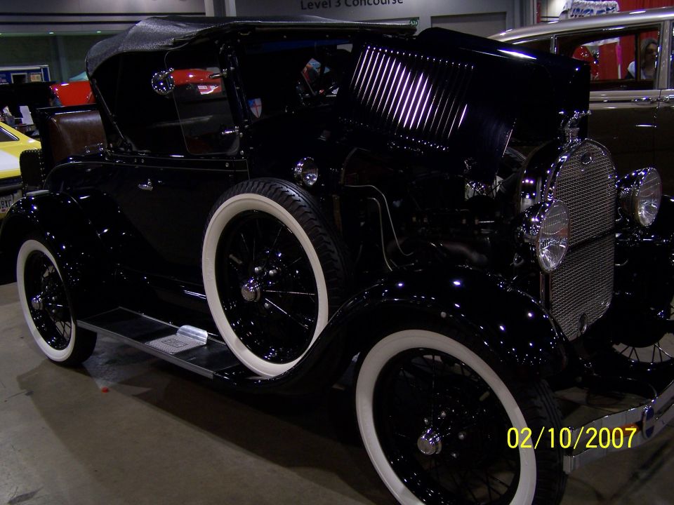 Black convertible with whitewall tires and a spare tire on the side. Hood is open, showing engine details