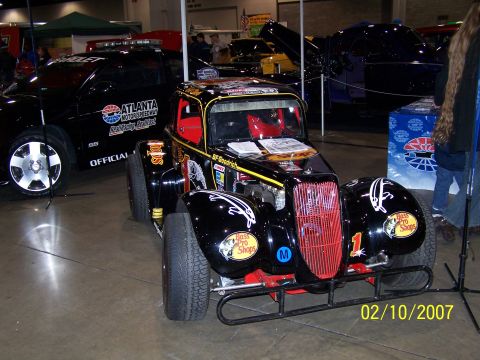 1979 Ford F-150 - A custom race car with sponsor decals is displayed indoors next to a support vehicle.