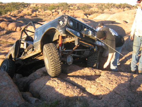1986 Ford Bronco - An off-road vehicle navigates challenging rocky terrain with assistance from bystanders.