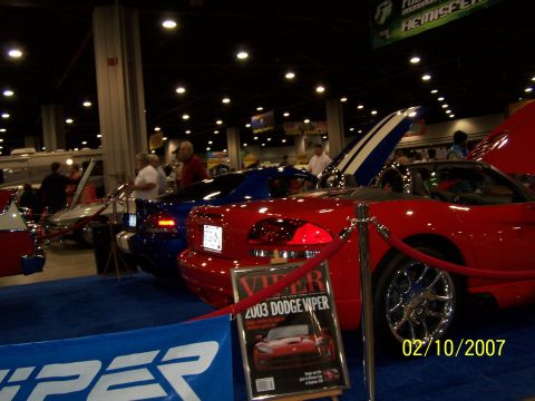 1979 Ford F-150 - A red convertible sports car is displayed at an indoor car show with other vehicles.