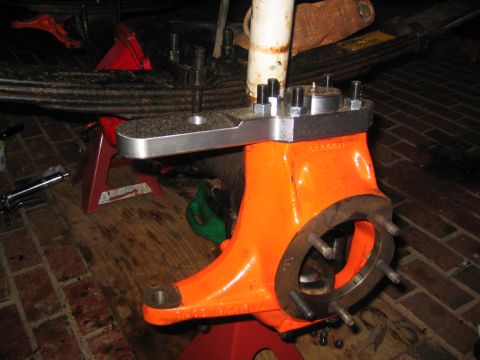 1979 Ford Bronco - Close-up of an orange axle housing with a metal bracket and bolts, supported by jack stands.