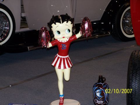 1979 Ford F-150 - A Betty Boop statue stands before a vintage vehicle at an event, with a decorative jug and tire visible nearby.