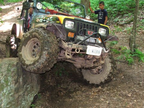 1996 Ford Bronco - This modified Jeep navigates a challenging off-road obstacle on a wooded trail.