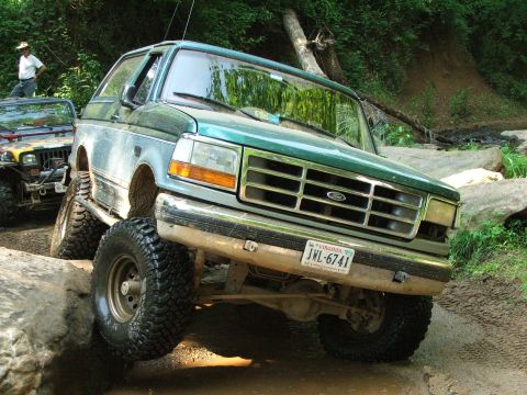 1996 Ford Bronco - Green 1996 Ford Bronco tackles a rocky off-road course, with a Jeep nearby.