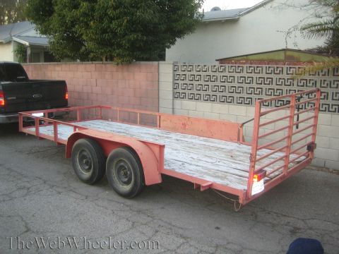 1987 Suzuki Samurai - A red utility trailer is hitched to a black pickup truck in a residential area.