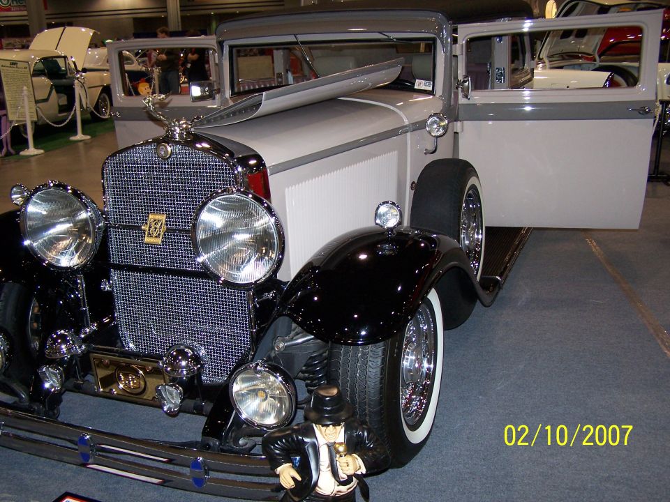 Black and cream sedan with open doors, chrome grille, and a hood ornament