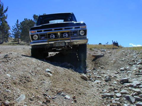 1979 Ford Bronco - Ford F-Series truck navigating a rough, rocky terrain under a clear blue sky.