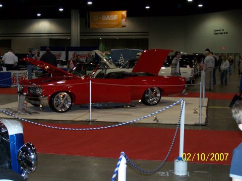 1979 Ford F-150 - A red convertible is displayed with its hood and door open at an indoor event.
