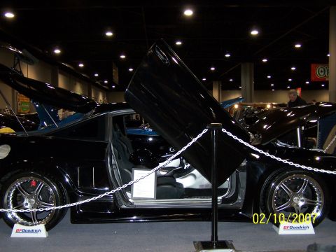 1979 Ford F-150 - A black custom sports car is displayed indoors with its gullwing doors open, revealing the interior and custom wheels.
