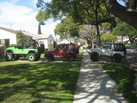 1987 Suzuki Samurai - Three Suzuki Samurai SUVs, one green, one red, and one white, are parked on a residential street.
