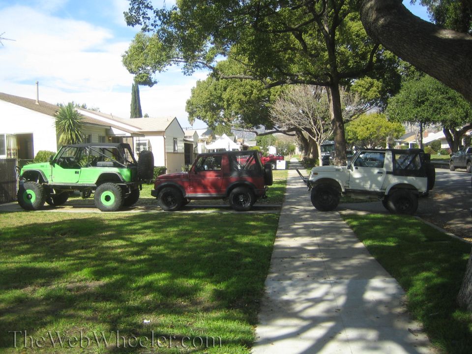 Three 1987 Suzuki Samurai SUVs parked on a sidewalk and lawn