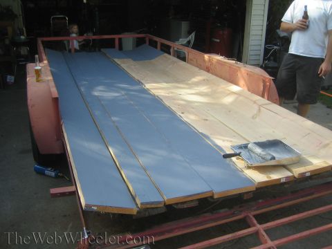 1987 Suzuki Samurai - A trailer is being loaded with lumber, some of which is being painted blue.