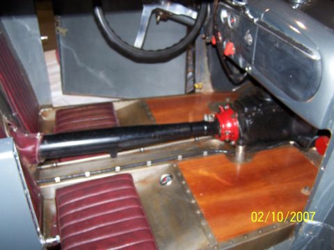 1979 Ford F-150 - The interior of a custom vehicle features red upholstered seats, polished wooden floor panels, and a prominent transmission tunnel with a r…
