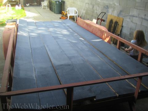 1987 Suzuki Samurai - Trailer bed being covered with new wooden planks, with a child observing.
