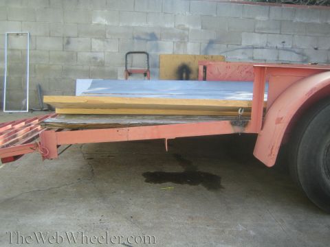 1987 Suzuki Samurai - A trailer is loaded with building materials and parked in front of a wall.