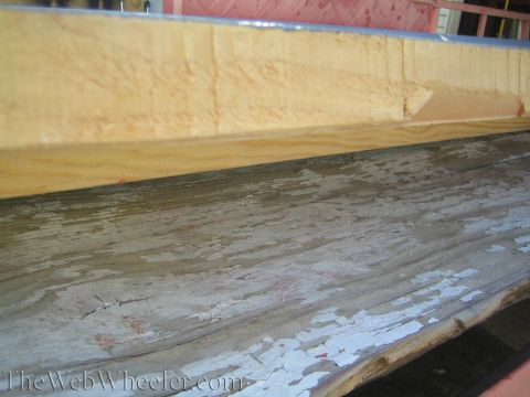 1987 Suzuki Samurai - A close-up view of a weathered wooden surface with peeling paint, under a wooden beam.