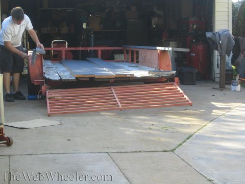 1987 Suzuki Samurai - Man working on a trailer loaded with metal sheets in a driveway.