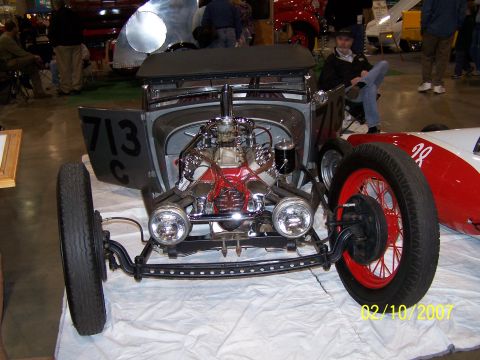 1979 Ford F-150 - A custom hot rod with a powerful engine is displayed indoors next to a red and white race car.