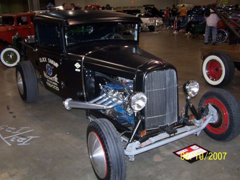1979 Ford F-150 - Custom black hot rod pickup truck with a prominent V8 engine and side exhaust pipes on display.