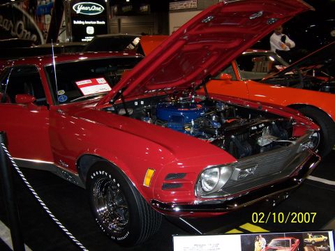 1979 Ford F-150 - A red 1970 Ford Mustang Mach 1 is displayed with its hood open, revealing the engine, at an indoor car show.