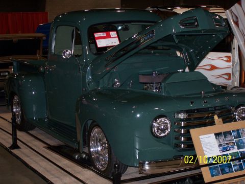 1979 Ford F-150 - A classic green Ford pickup truck is displayed with its hood open, revealing the engine bay.
