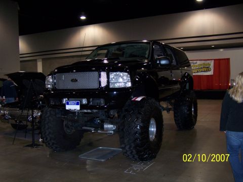 1979 Ford F-150 - This black SUV features oversized tires and a prominent custom grille, displayed indoors.