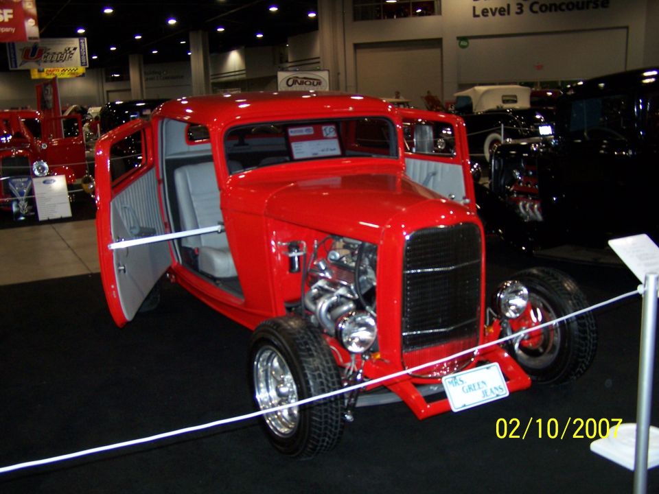 Red hot rod with open doors, exposed engine, and a sign that reads "Mrs. Green Jeans"