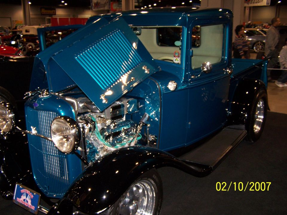 Blue custom hot rod pickup truck with hood open, showing engine. Black fenders and running boards
