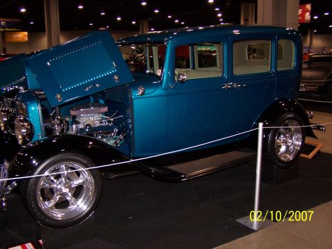 1979 Ford F-150 - A teal-colored sedan with its hood open is displayed indoors, custom wheels and exposed engine components.