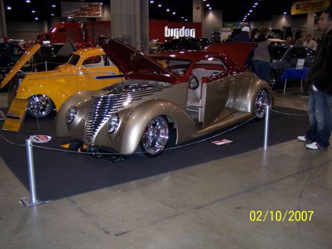1979 Ford F-150 - A customized coupe is displayed indoors with its hood open, revealing the engine and interior.