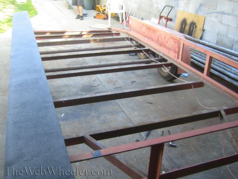 1987 Suzuki Samurai - The frame of a trailer is shown during construction, with metal beams and a wheel visible.