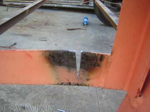 1987 Suzuki Samurai - Close-up of an orange metal frame showing a V-shaped cut and signs of rust and damage.