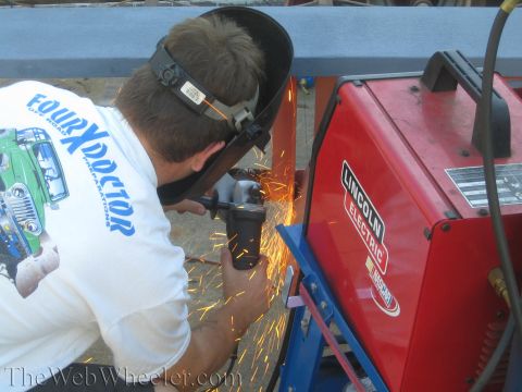 1987 Suzuki Samurai - A person is using an angle grinder, creating sparks next to a red Lincoln Electric welder.