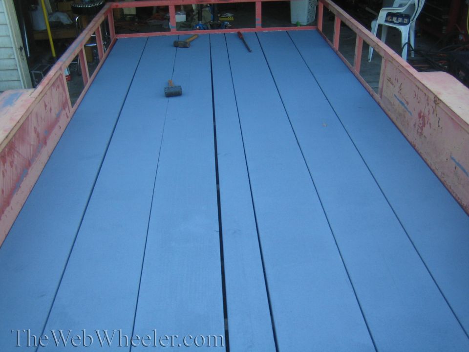 Trailer bed with blue painted planks and tools. The Web Wheeler.com watermark visible