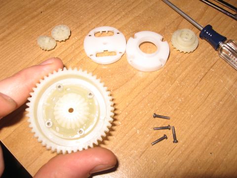 1990 Ford Bronco - Various plastic gears and screws are laid out on a wooden surface, suggesting a repair or assembly process.