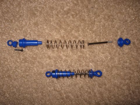 1990 Ford Bronco - Disassembled toy shock absorber parts laid out on a carpeted surface.