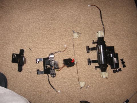 1990 Ford Bronco - RC car components are laid out on a carpeted surface, showing various mechanical and electronic parts.