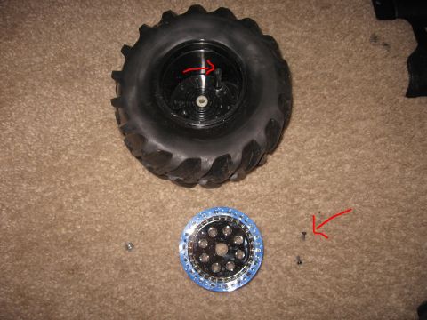 1990 Ford Bronco - A tire and wheel assembly, along with a separate wheel and screws, are laid out on a carpeted surface.