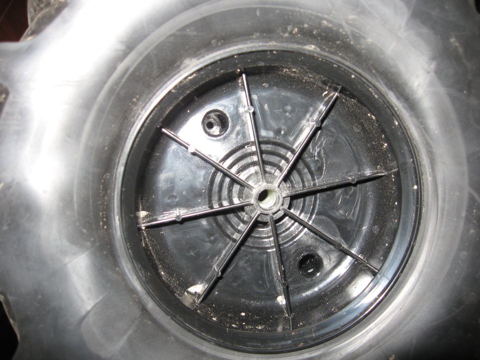 Close-up of a wheel hubcap interior with a central plastic fan-like structure and metal clips
