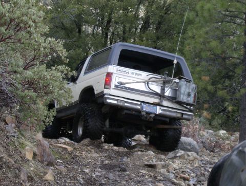 1986 Ford Bronco - This 1986 Ford Bronco navigates a challenging, rocky incline surrounded by trees.