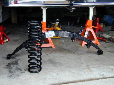1979 Ford Bronco - Suspension parts, including a coil spring and leaf spring, are laid out on a garage floor.