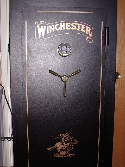 1985 Ford Bronco - A black safe with a Winchester logo and a cowboy graphic is shown, a digital keypad and a three-spoke handle.