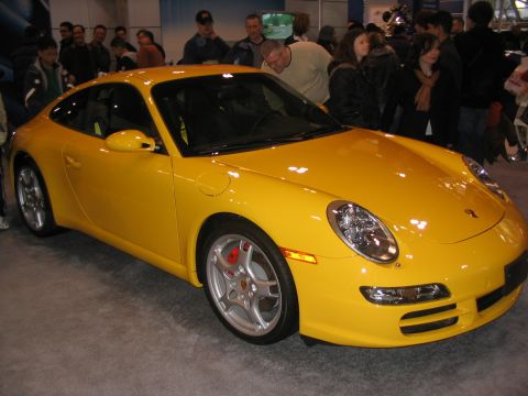 1993 Ford Taurus - A bright yellow Porsche 911 is displayed at an auto show, with spectators in the background.