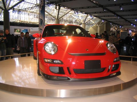 1993 Ford Taurus - A red Porsche 911 is showcased at an auto show with people in the background.