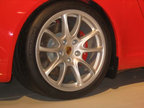 1993 Ford Taurus - Close-up of a red car's wheel, a silver alloy rim with the Porsche crest and a red brake caliper.