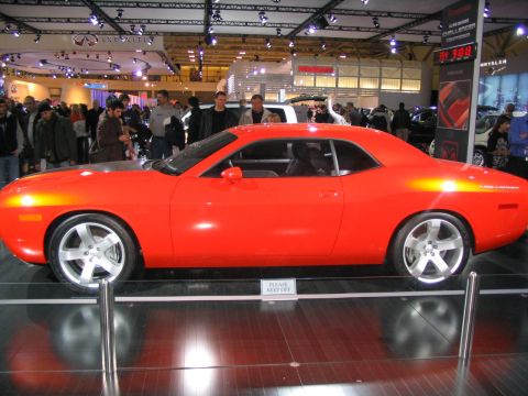 1993 Ford Taurus - A red Dodge Challenger concept car is displayed at an auto show with people in the background.