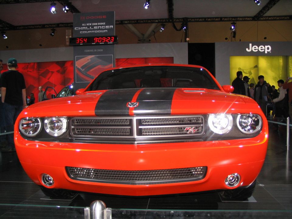 Orange 2008 Dodge Challenger front view with black racing stripes and a countdown clock in the background