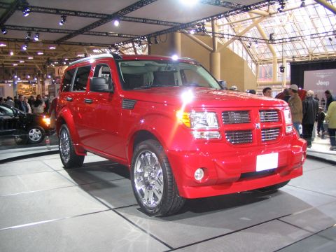 1993 Ford Taurus - A red SUV is displayed indoors with other vehicles and people in the background.
