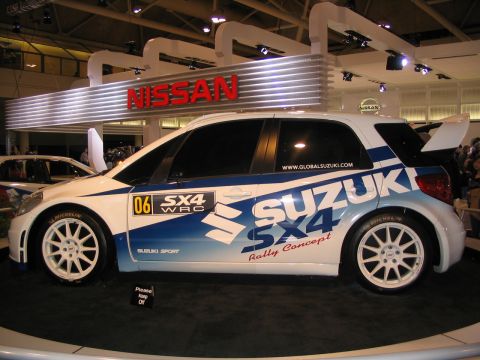 1993 Ford Taurus - A Suzuki SX4 WRC rally car is displayed at an auto show, with 'Nissan' signage visible in the background.