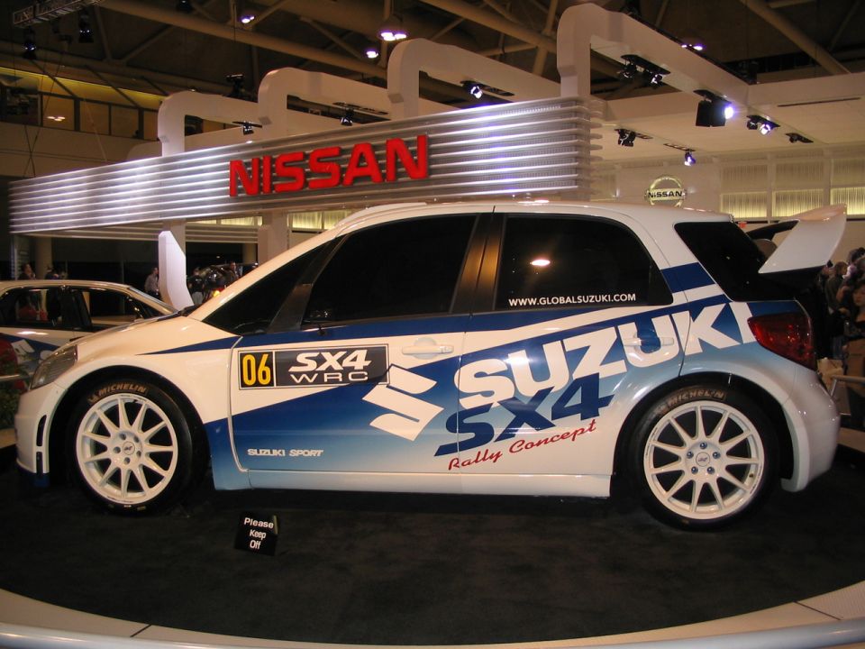Suzuki SX4 WRC rally car with 'Suzuki Sport' and 'Rally Concept' decals, white wheels, and a spoiler